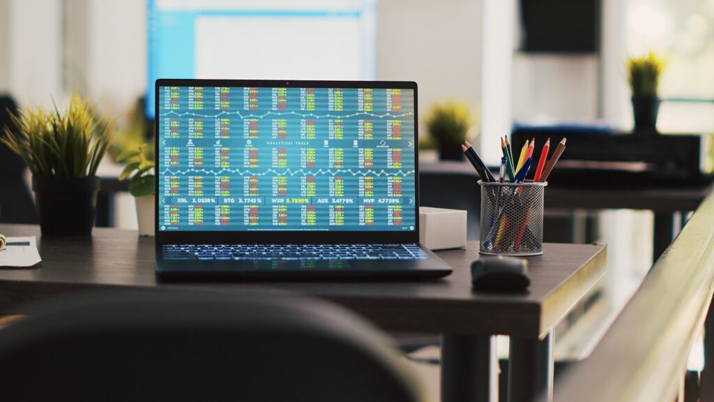 business files on desk next to notebook showing forex trading indexes prices
