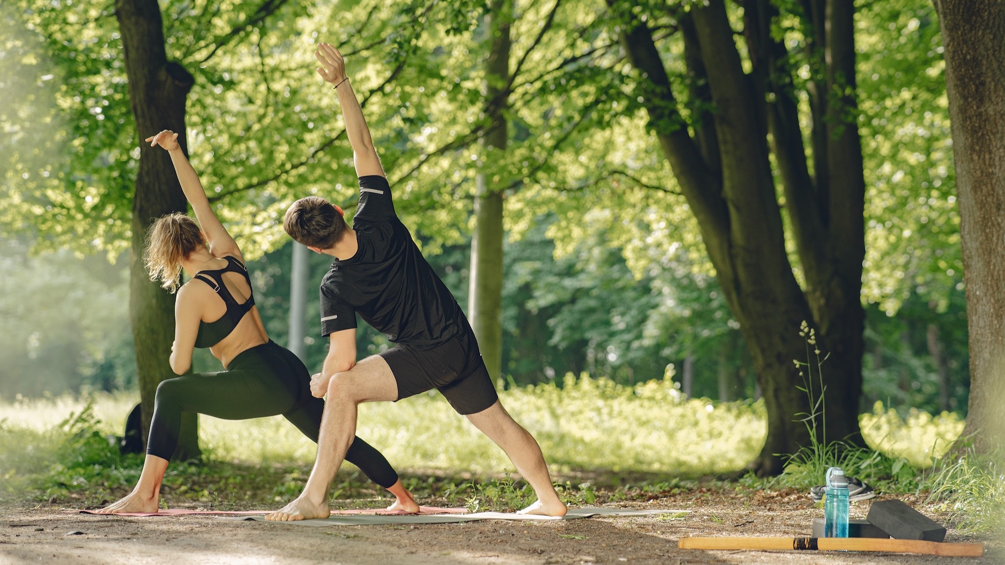 man and woman doing yoga exercises in the park